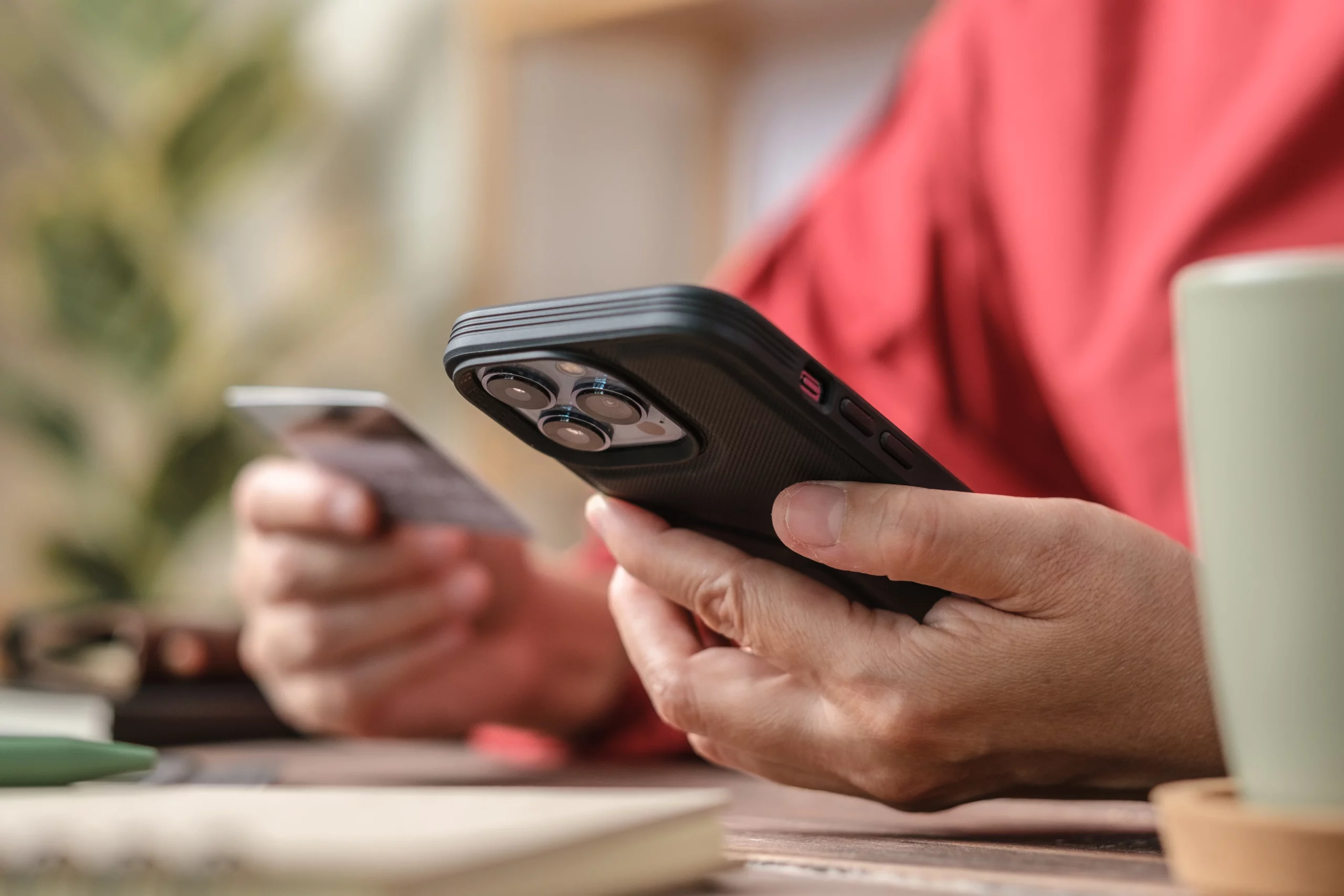 Person in a red sweater holding a smartphone and credit card while viewing a text message, illustrating consumer debt concerns and FDCPA protections against debt collector text messages in Missouri.